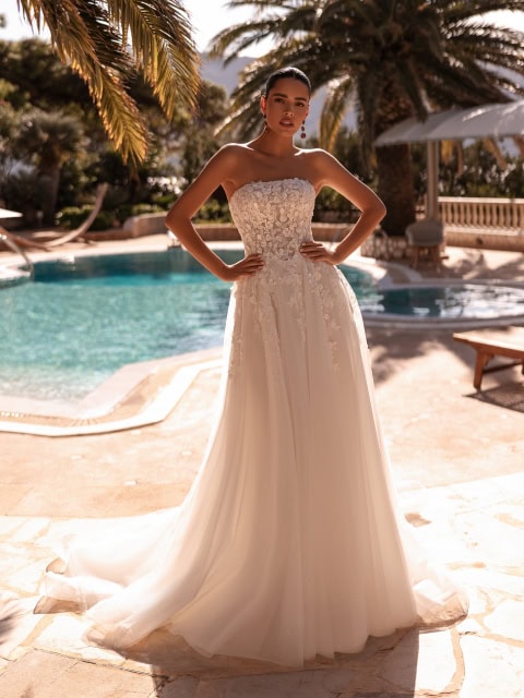 NEW COLLECTION 🤍
Ein eleganter, schulterfreier Ausschnitt und moderne, florale Spitze vereinen sich in diesem Brautkleid zu einem klaren und dennoch romantischen Statement.
Das sanft strukturierte Mieder ist mit Perlenverzierungen geschmückt, die auf den zartesten Tülllagen funkeln, während der passende Schleier in raffinierter Harmonie vollendet.